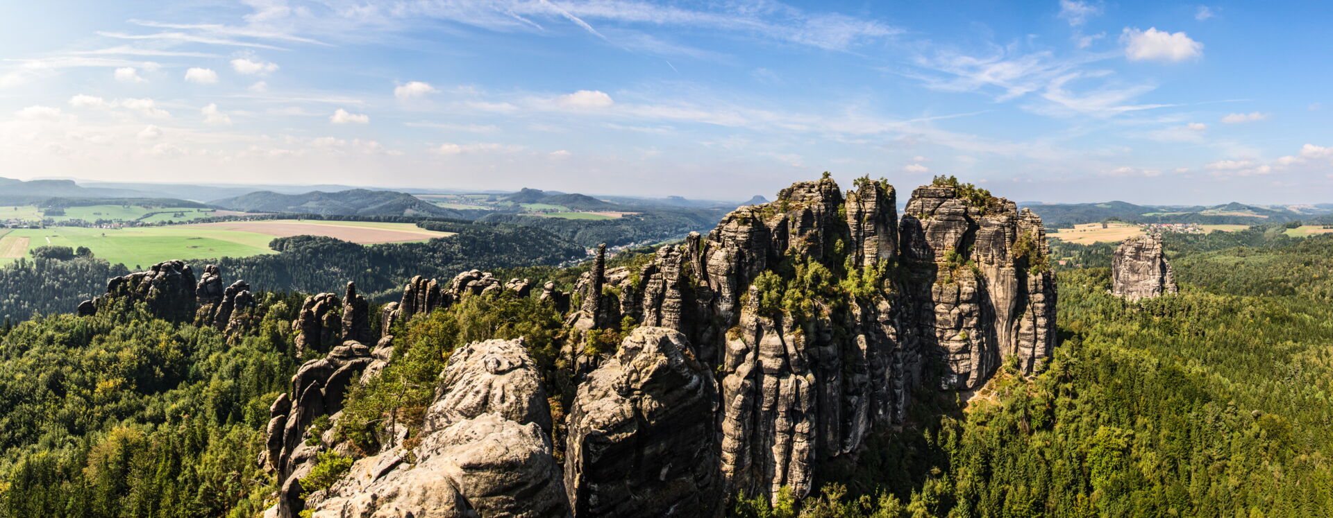 Panorama des Elbsandsteingebirges mit bizarren Felsformationen und Wäldern.