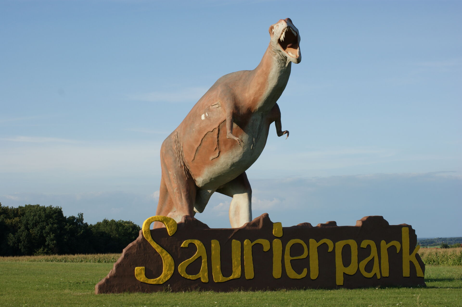 großer brüllender Saurier steht auf der Wiese des Eingangs zum Saurierpark Kleinwelka
