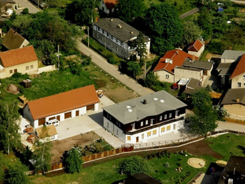 Luftaufnahme eines Wohngebiets mit Häusern und Gärten, Straßen dazwischen.